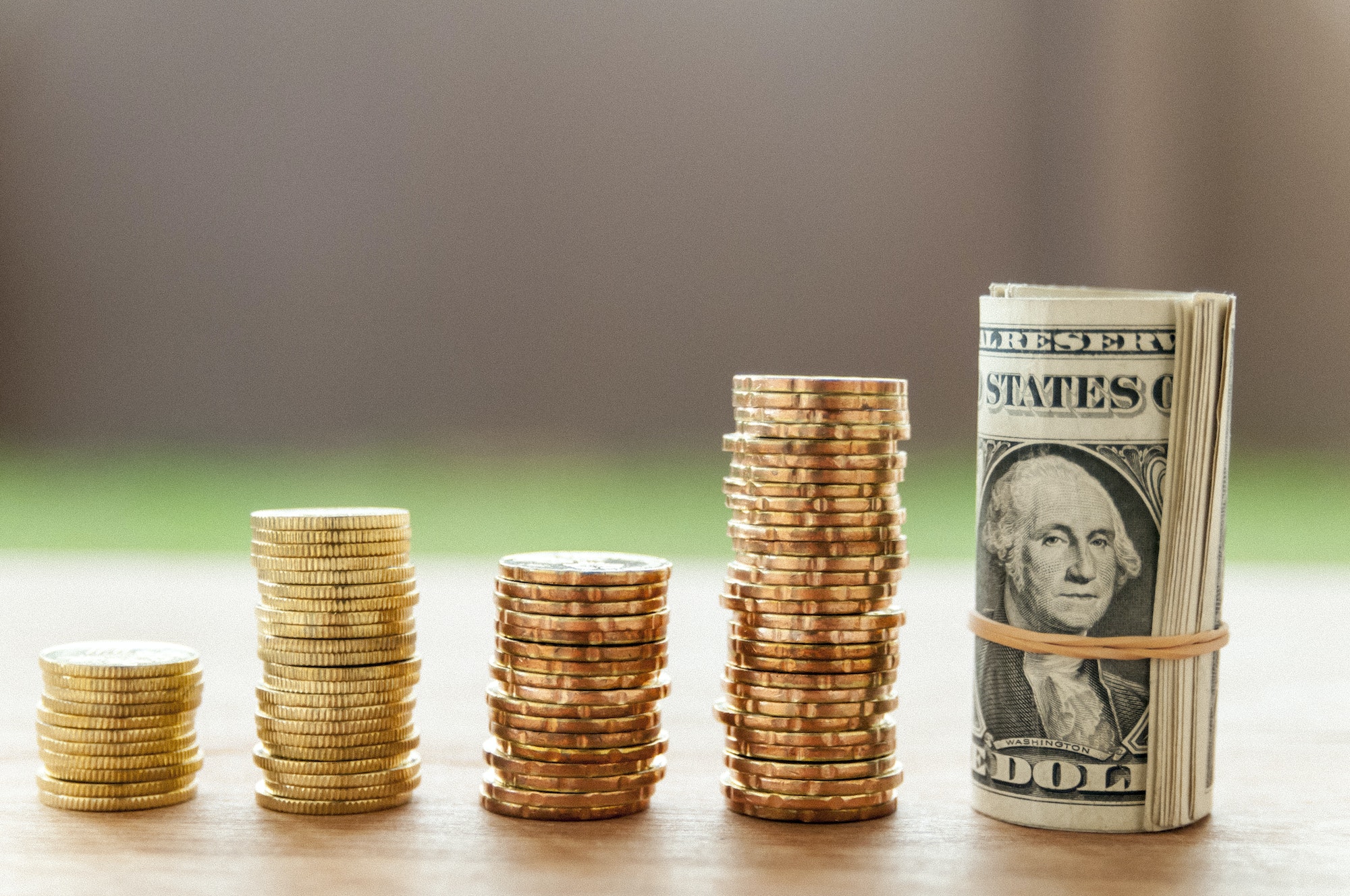 Stacks of gold coins and US dollar bill forming bar graph